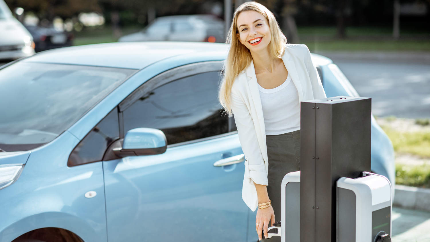 Uśmiechnięta kobieta ładuje elektryczny samochód, który jest zwolniony z podatku BPM w Holandii.