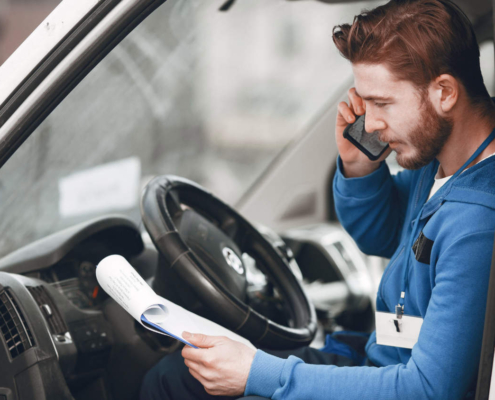 Przedsiębiorca siedzący w vanie i rozmawiający przez telefon ze swoim księgowym o podatku BPM w Holandii i zmianach w 2025 roku nadchodzących dla samochodów dostawczych.